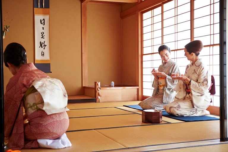 Three women in kimono participate in a tea ceremony