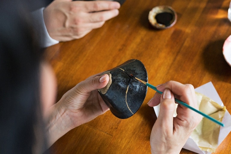 A cracked Japanese-style ceramic cup that has been repaired with gold lacquer