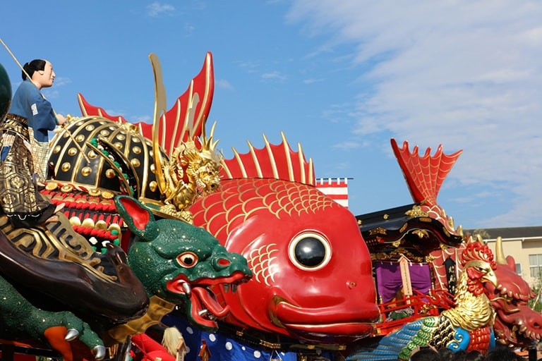 An array of brightly colored parade floats under a blue sky