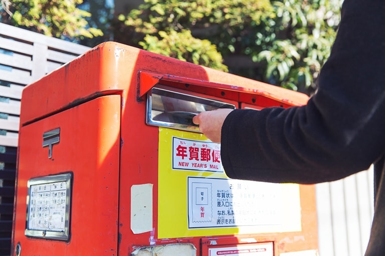 A person putting a bundle of postcards in a post box