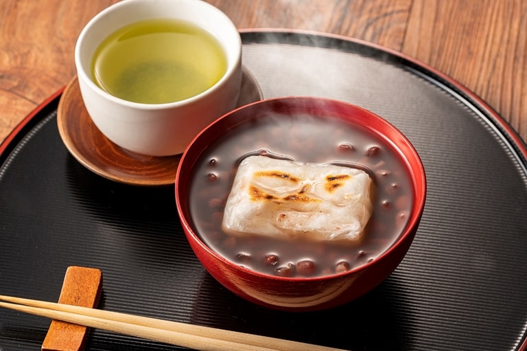 A tray with a bowl of zenzai and a cup of green tea