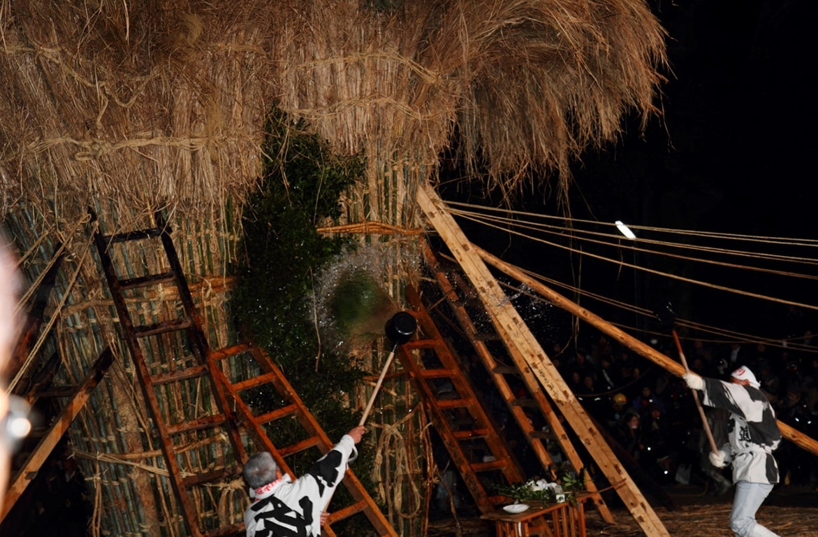 Two giant bamboo and rope torches are pulled upright