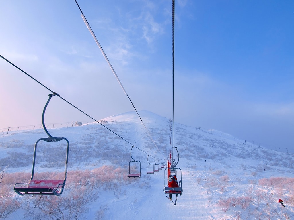 Skiers riding a chairlift to the top of a mountain