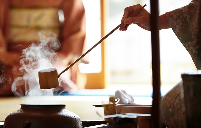 Scene from a traditional tea ceremony, as hot water is ladled from a clay pot