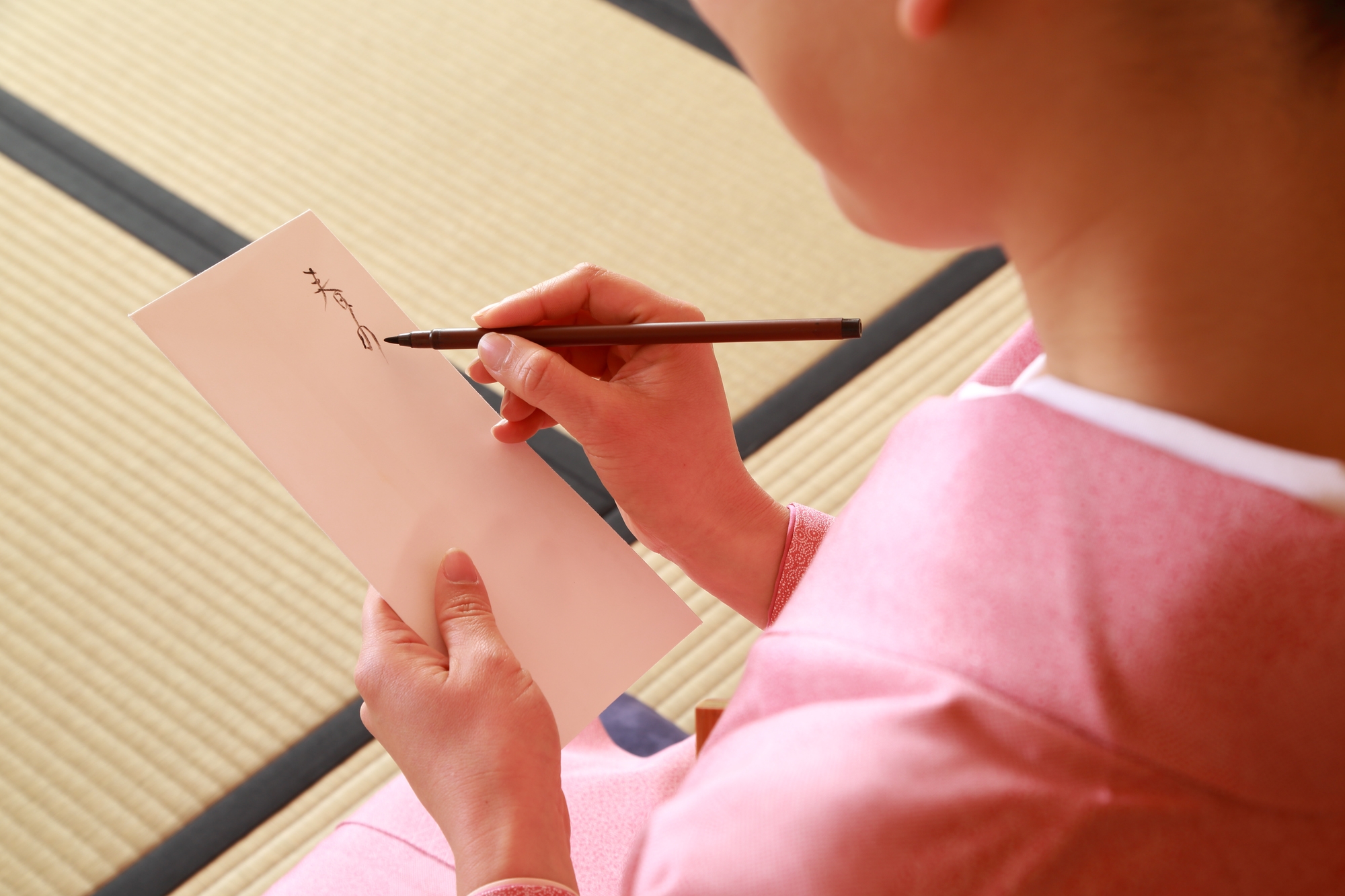 A woman in kimono starts to write on a paper