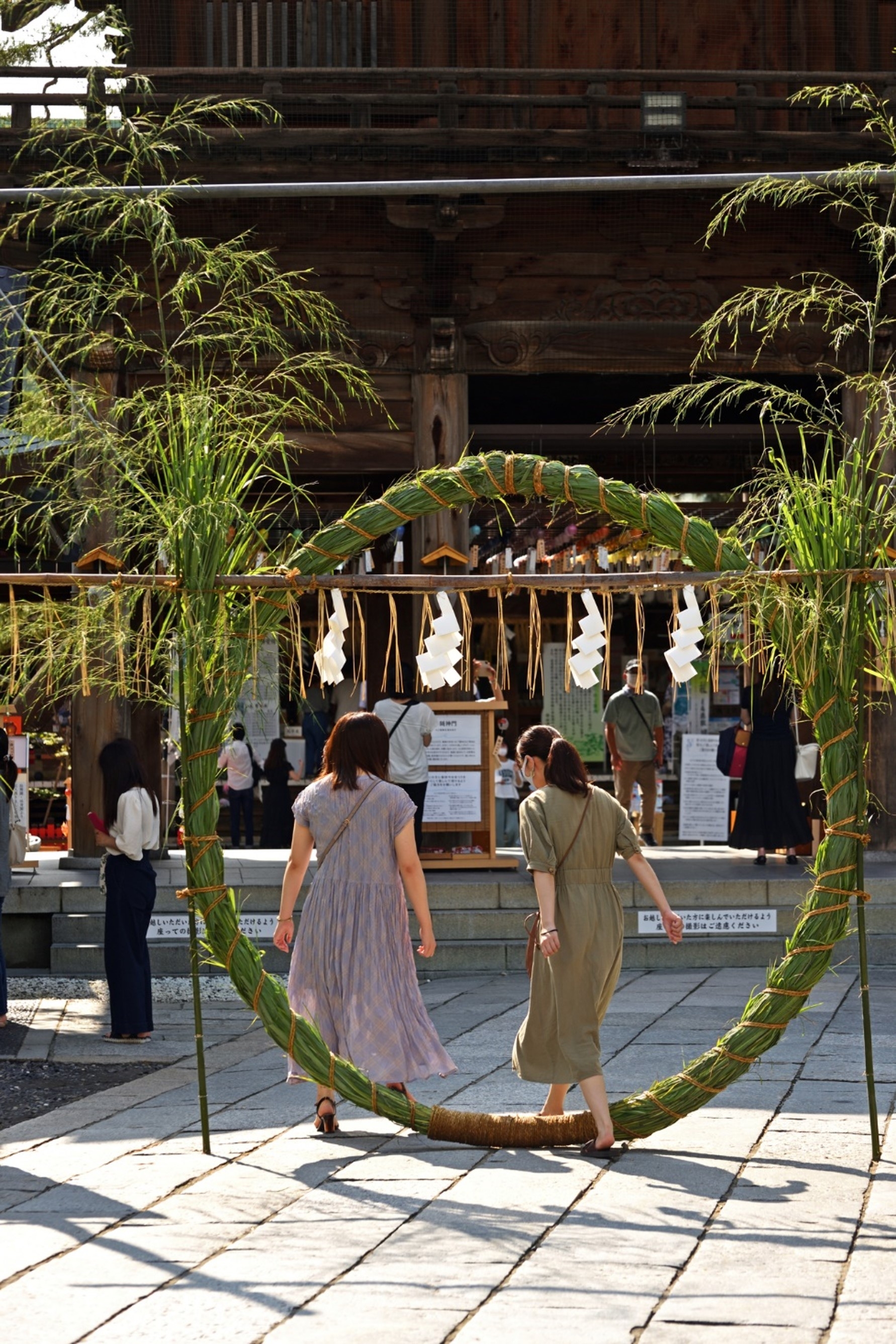 Visitors at a shrine walking through a hoop of woven branches