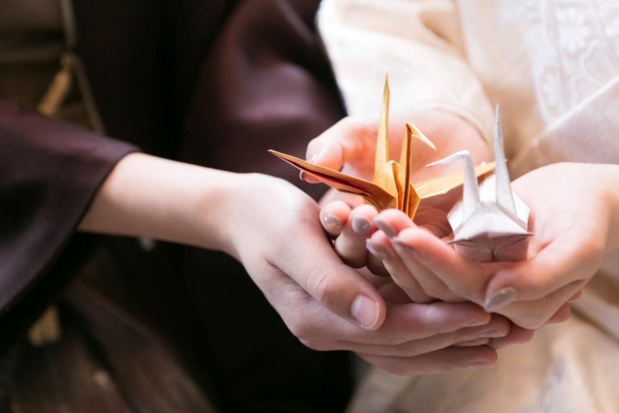 Groom and bride holding origami cranes together