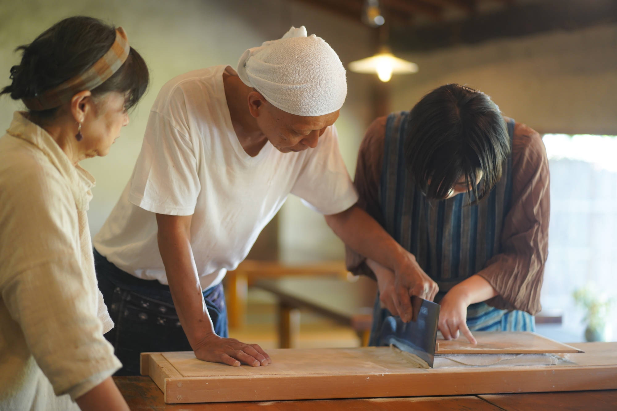 A chef teaching a tourist how to produce noodles