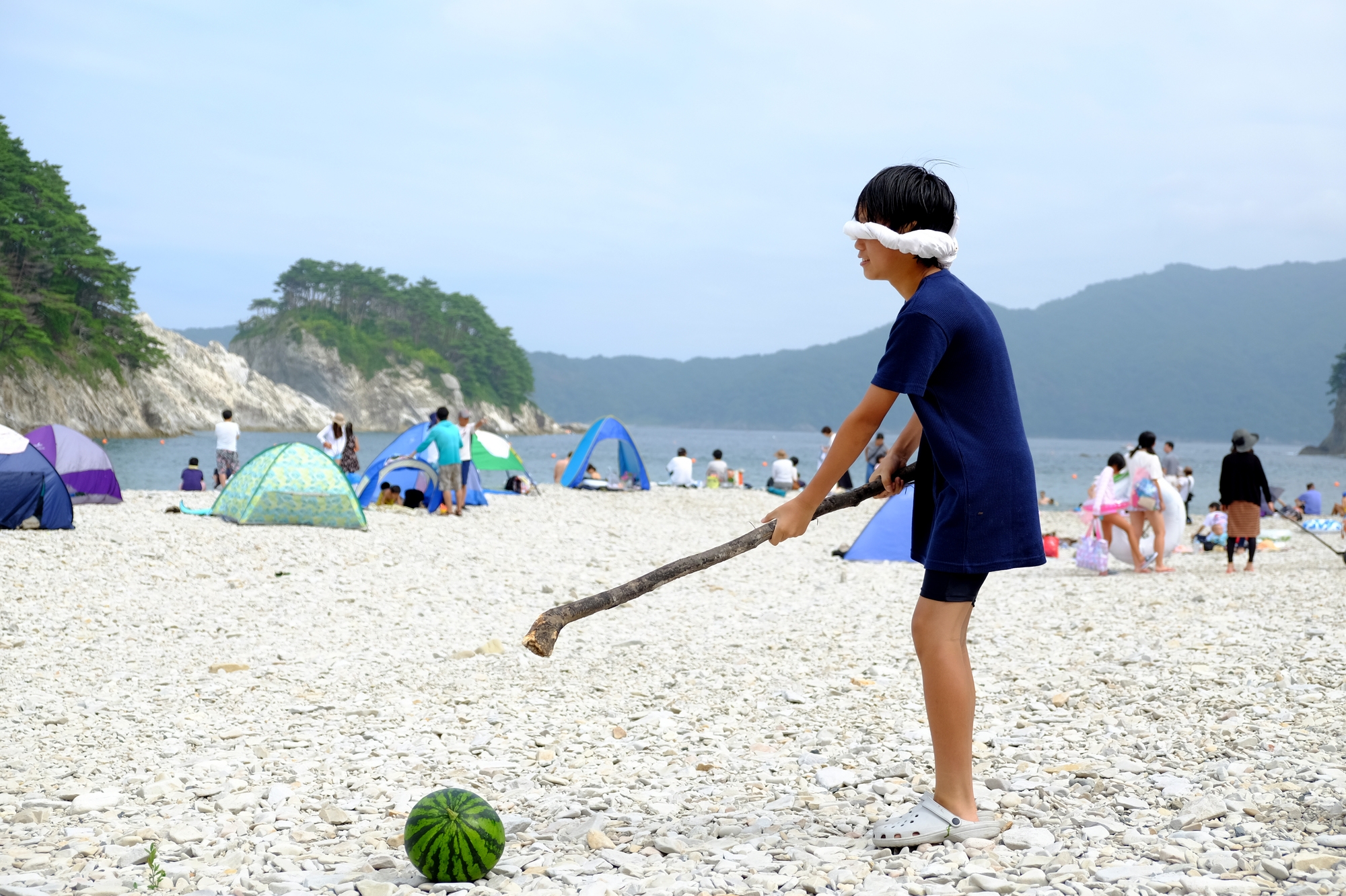 A child trying to hit a watermelon with a stick while blindfolded