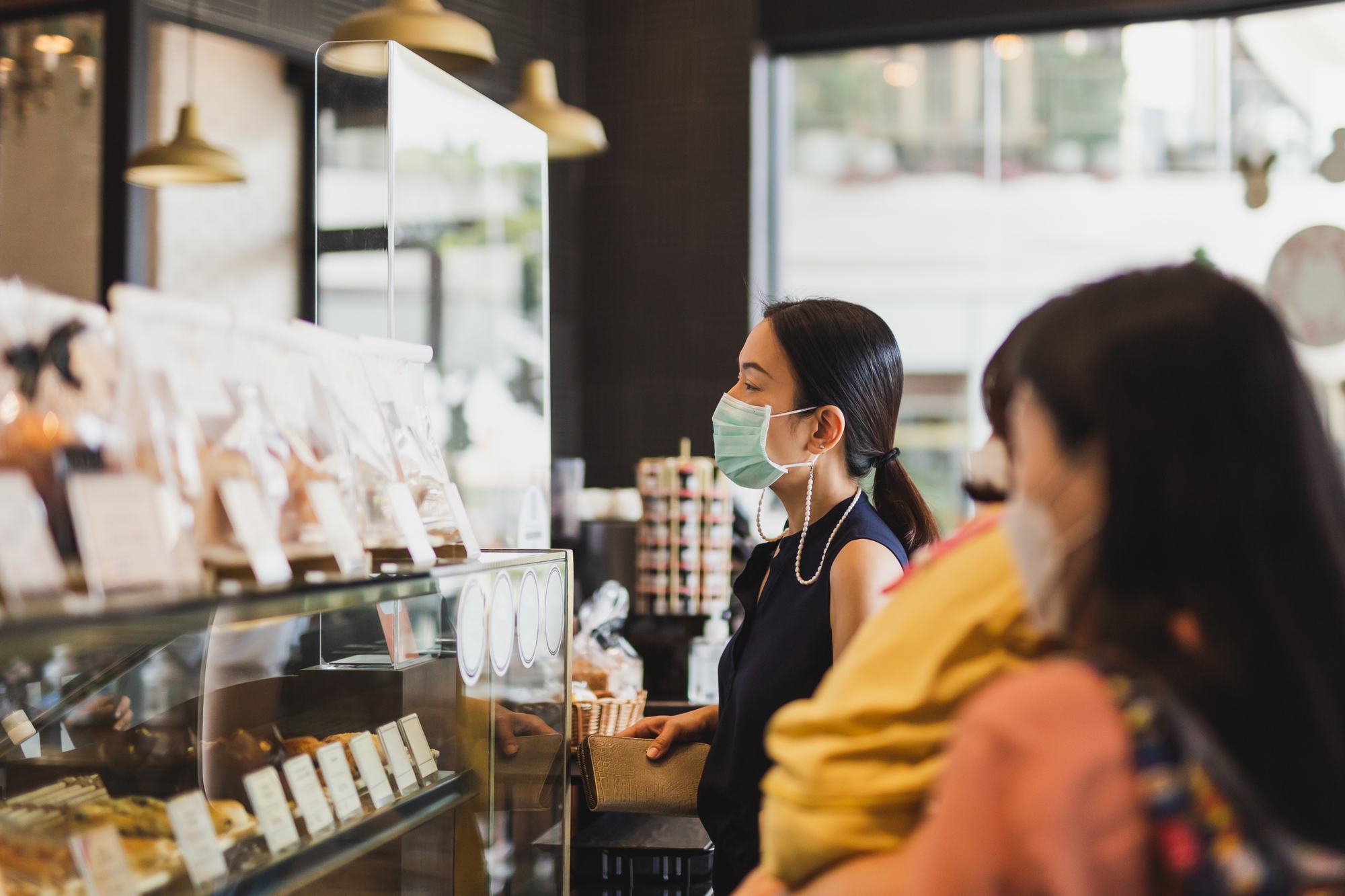 A woman with a mask orders food at a store