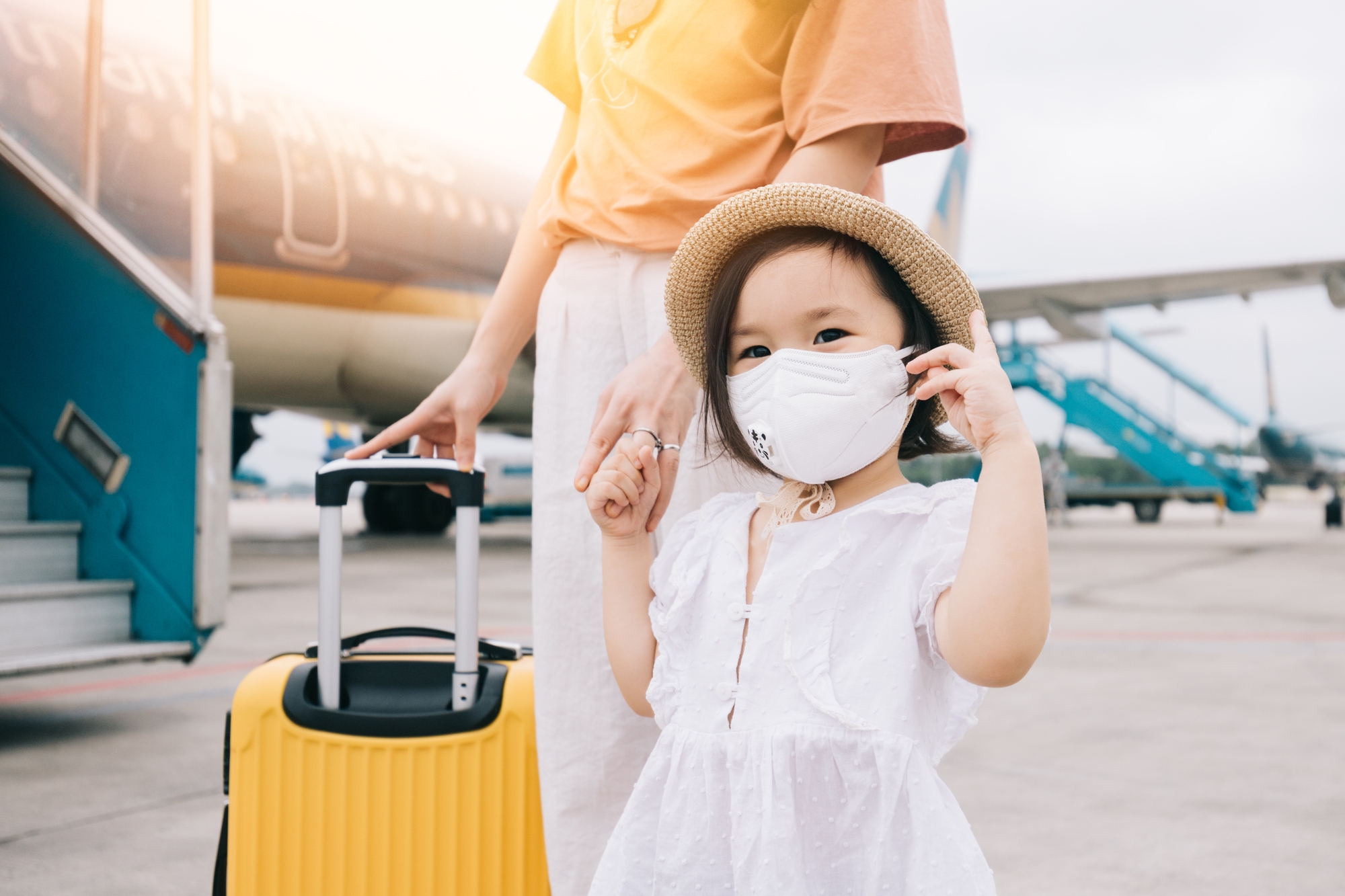 A small girl with her mother boarding an airplane