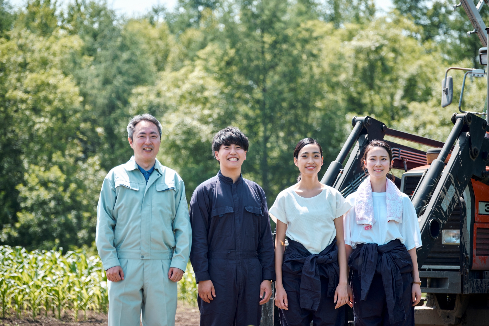 A middle-age farmer standing outside with three young farmers