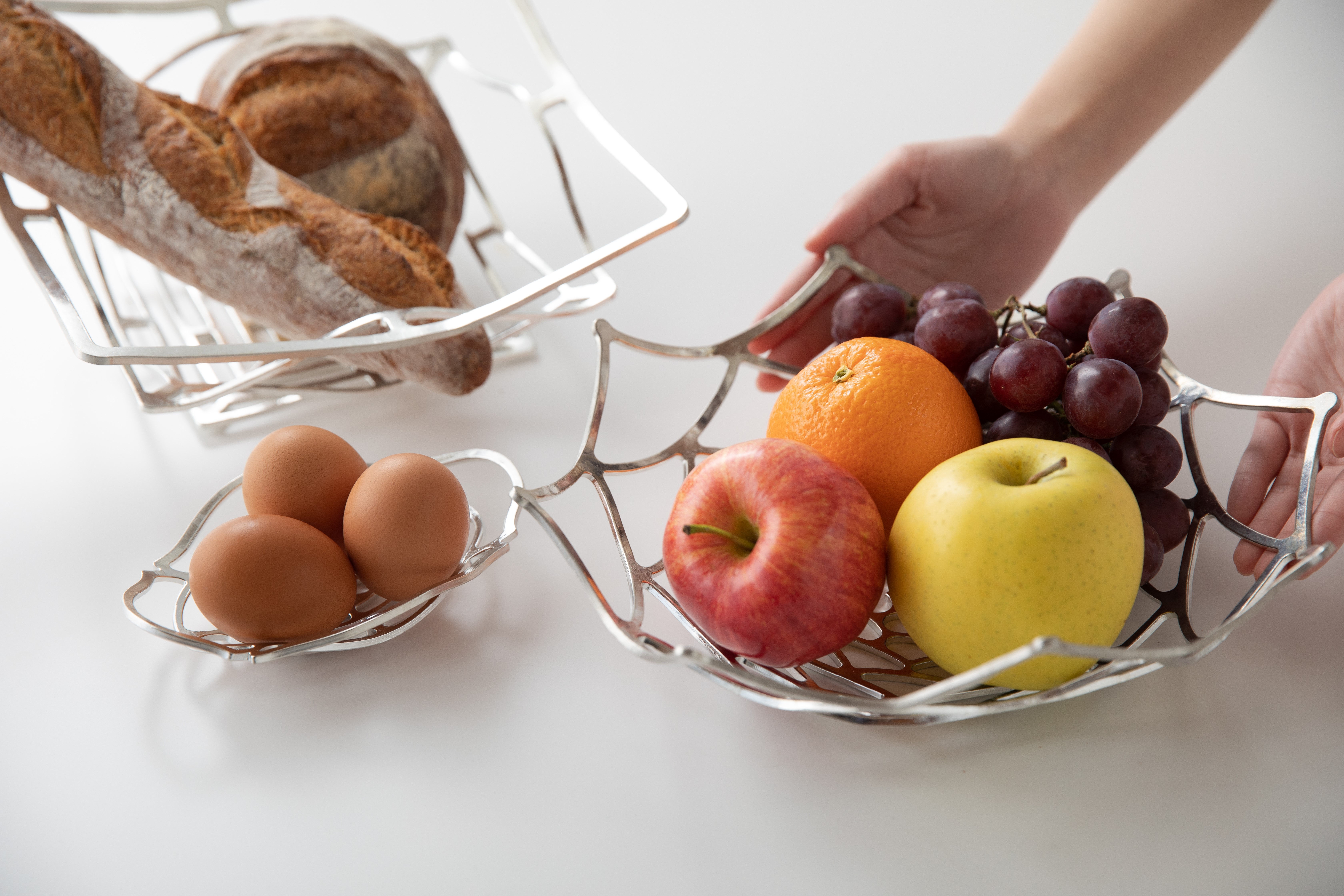 Bread, fruit, and eggs in baskets made from thin strands of tin