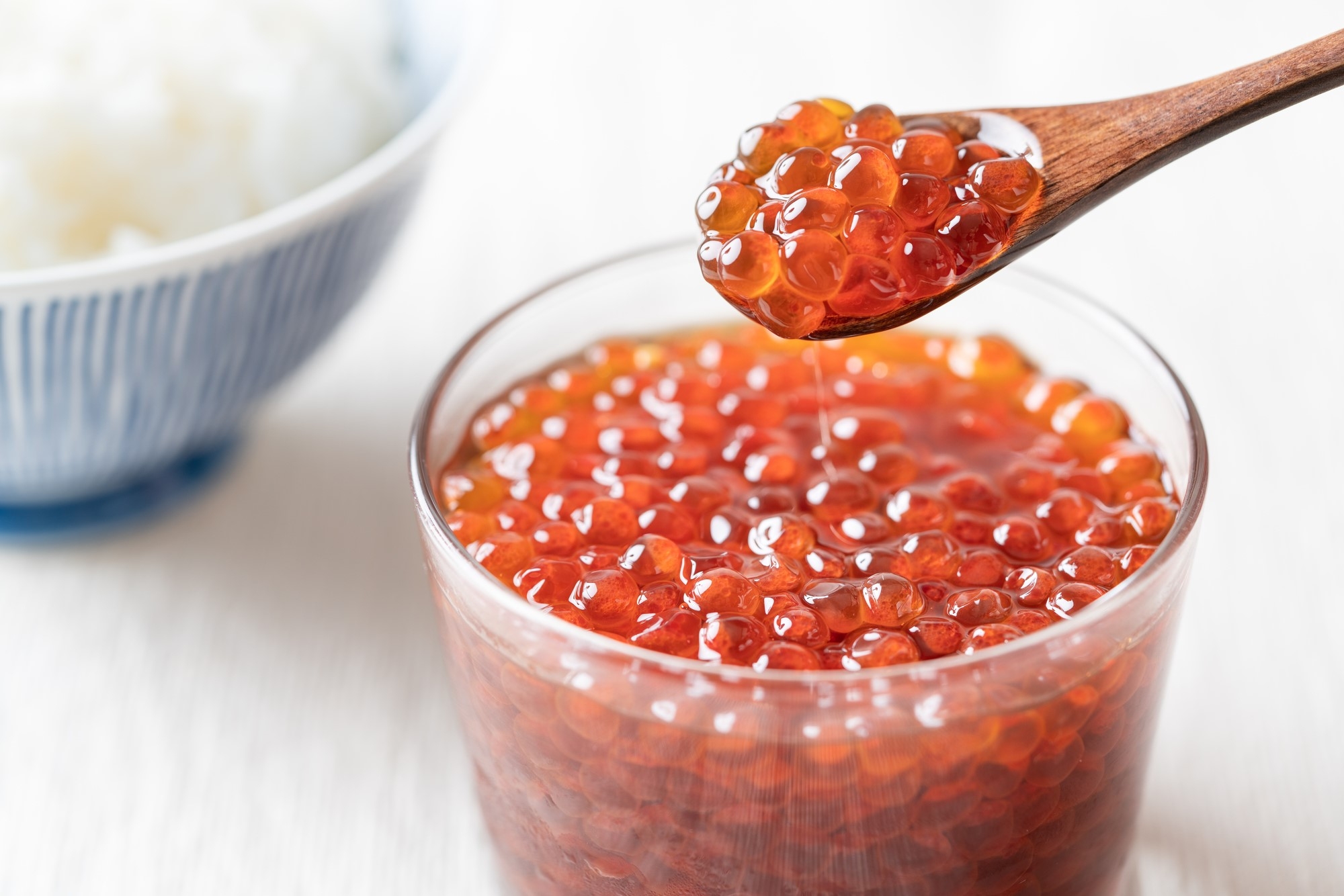 Salmon roe being spooned out of a glass cup