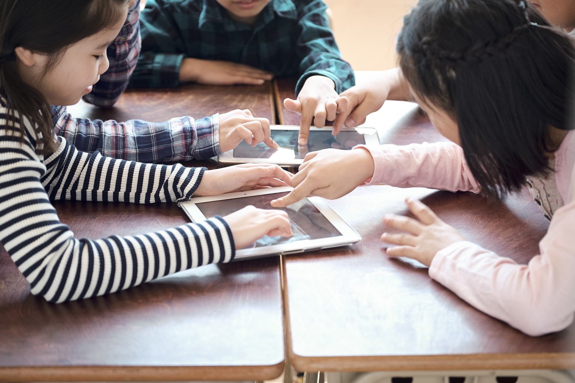 Children in a classroom tapping a tablet