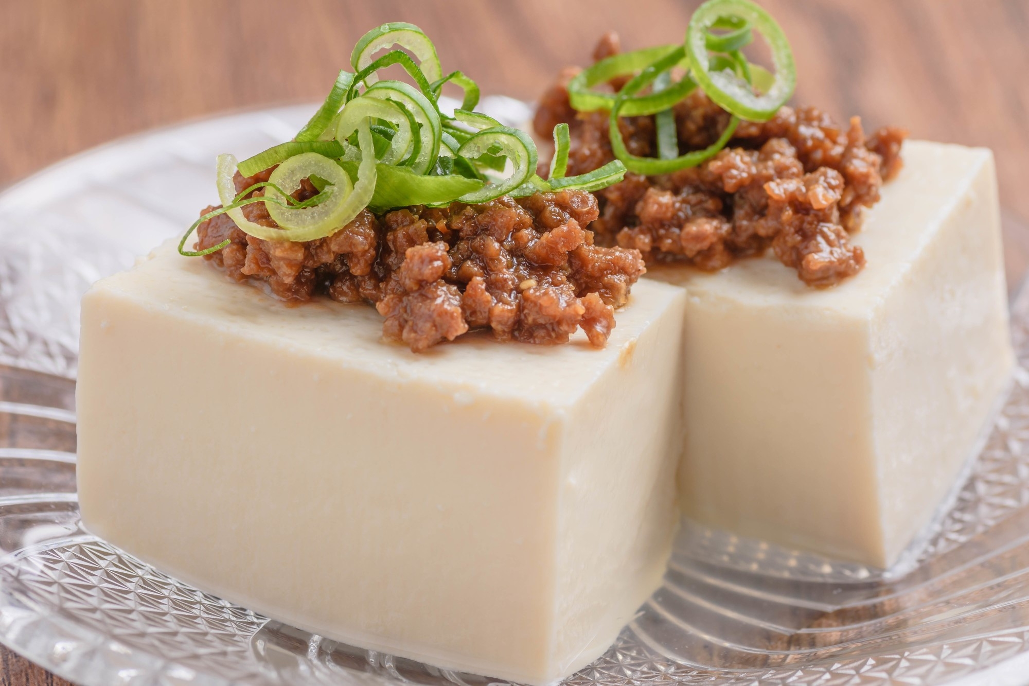 Blocks of tofu topped with soy-based spiced meat and sliced onion