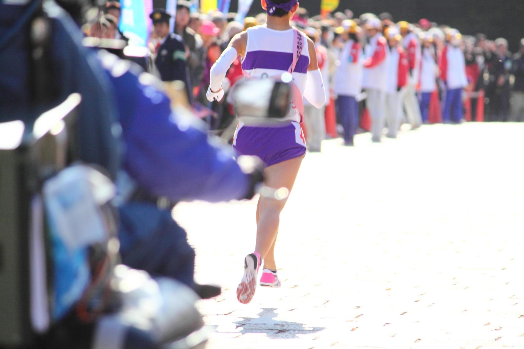 A runner in in ekiden race, followed by a motorbike