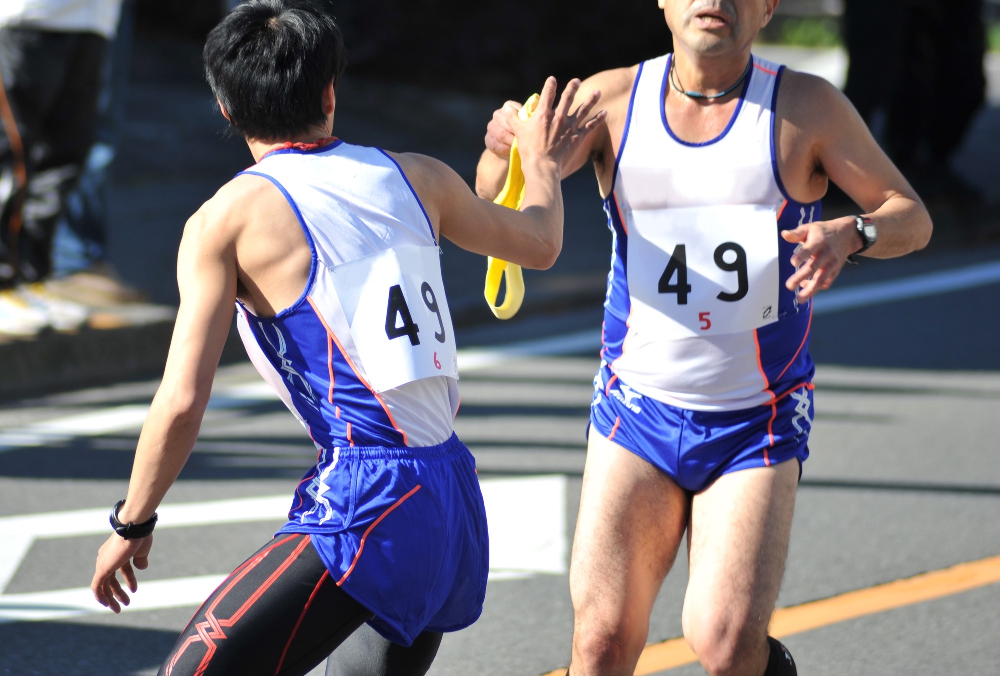 An ekiden runner passes his relay sash to a teammate