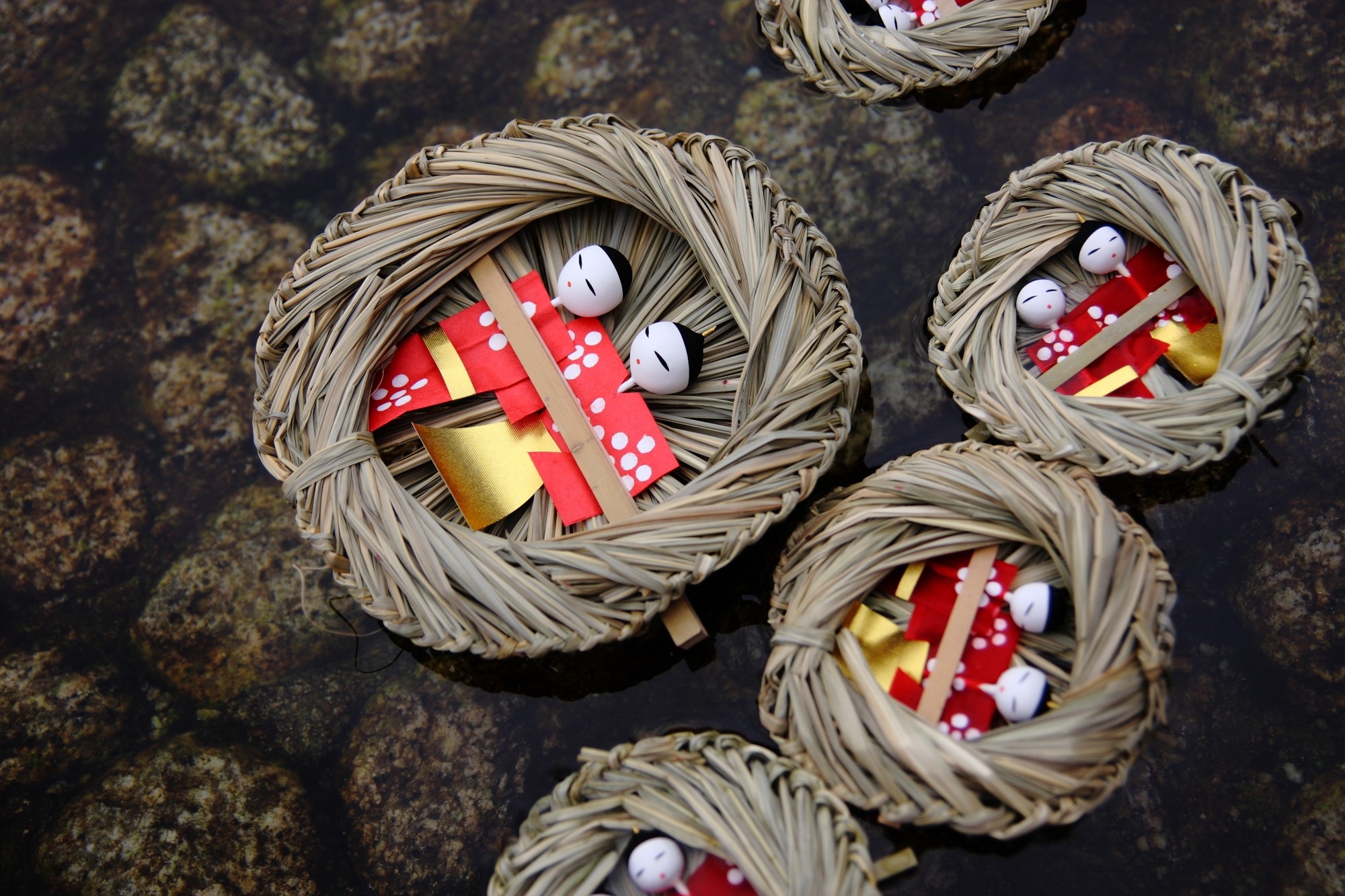 Paper dolls being floated on straw rafts