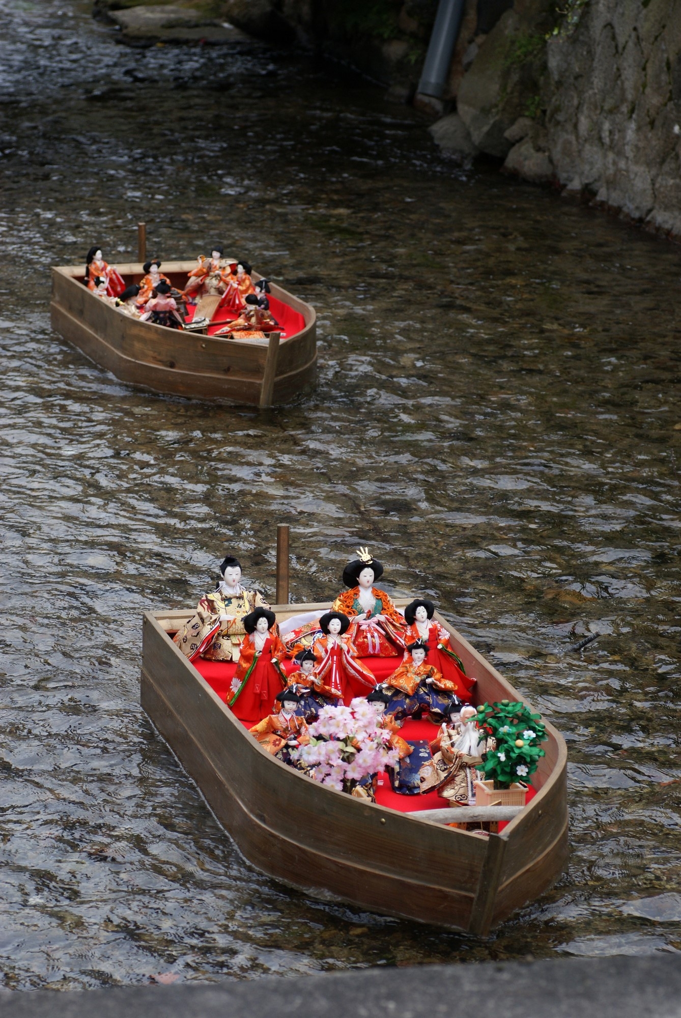 Elaborate wooden model boats carrying hina dolls down a river