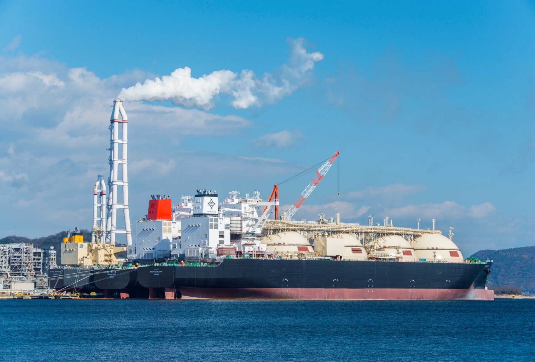 An LNG tanker ship in front of a refinery