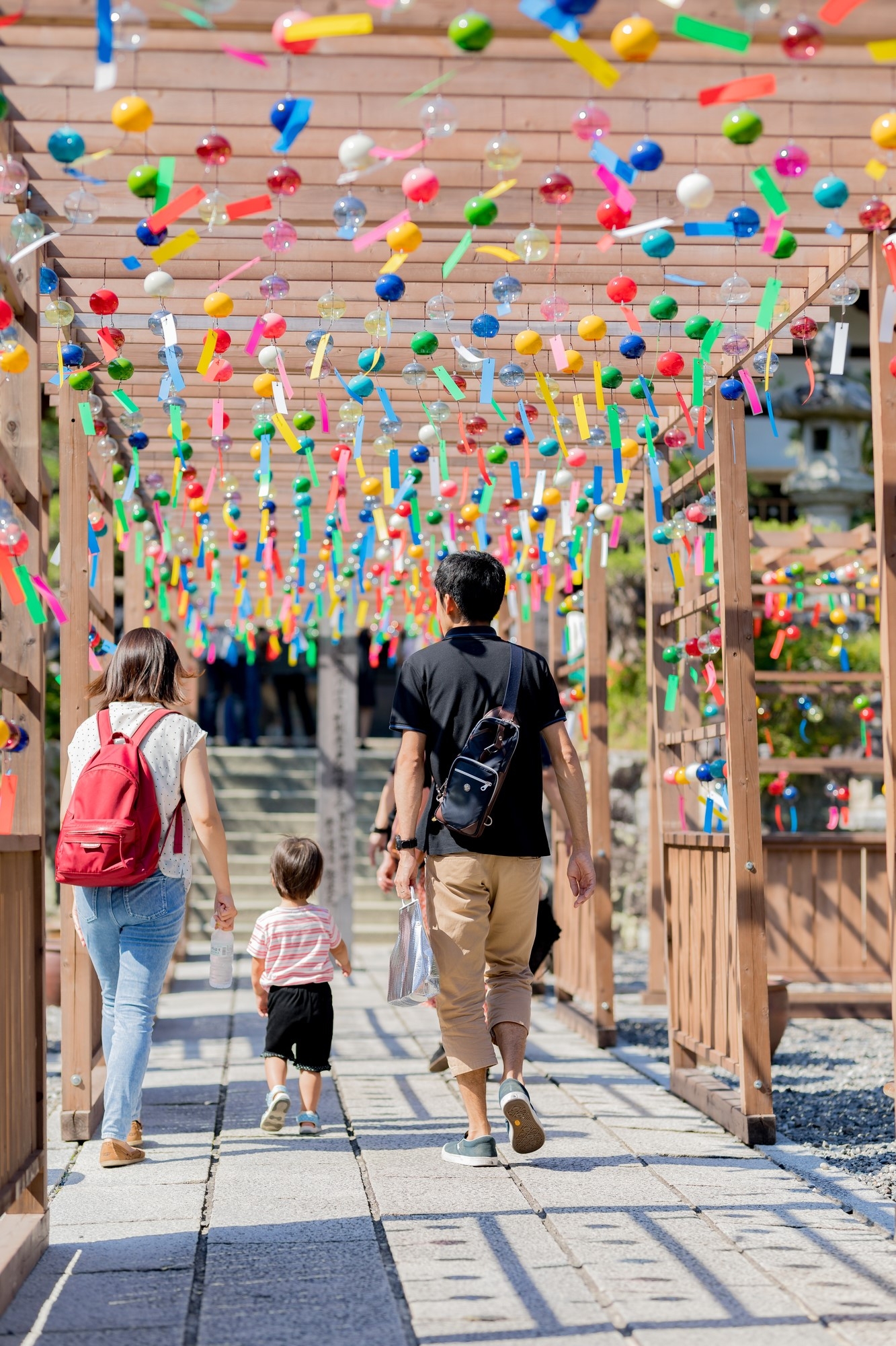 A family walking under wind chimes