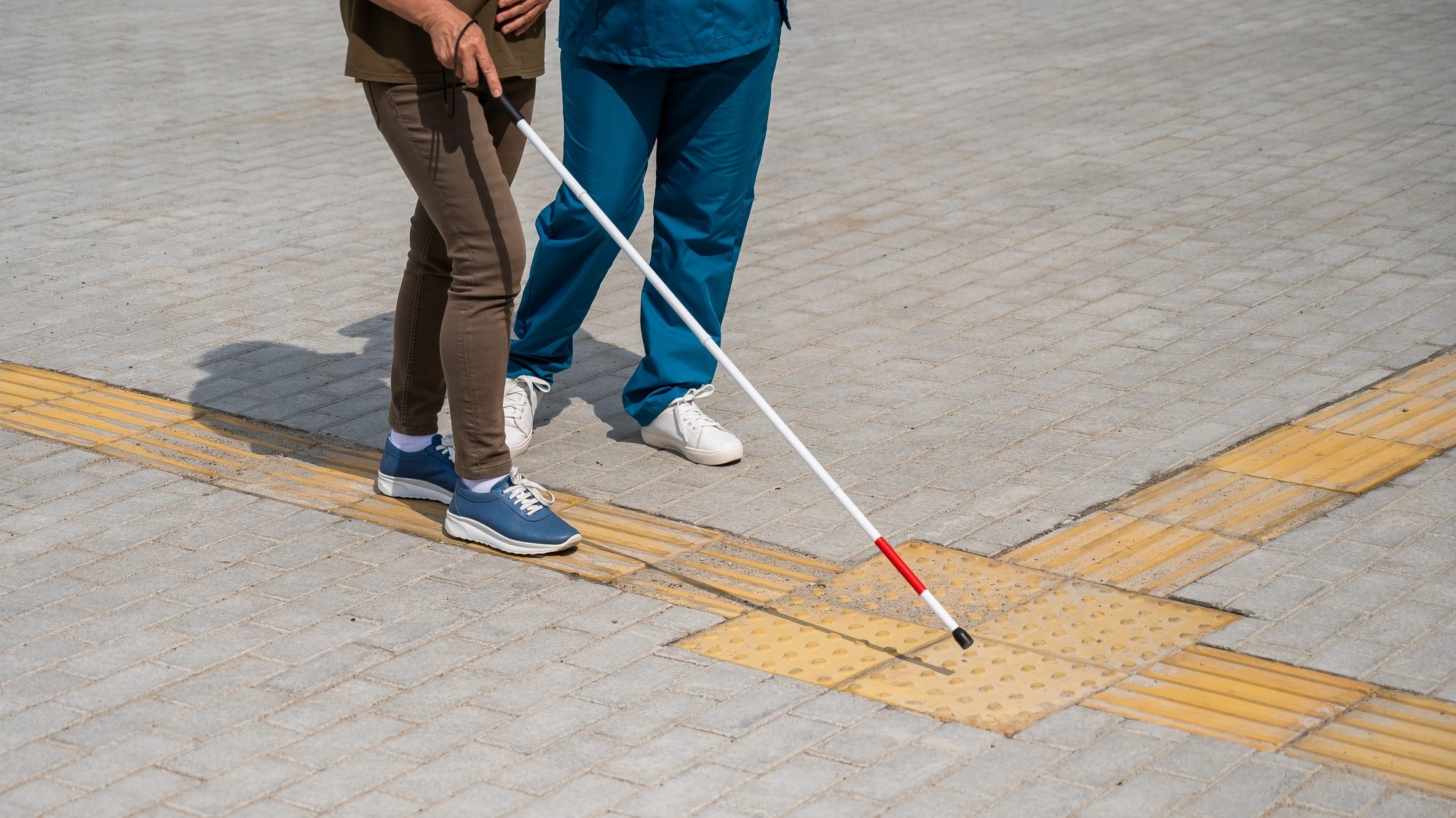 A visually impaired person familiarizing  themselves with tactile paving blocks